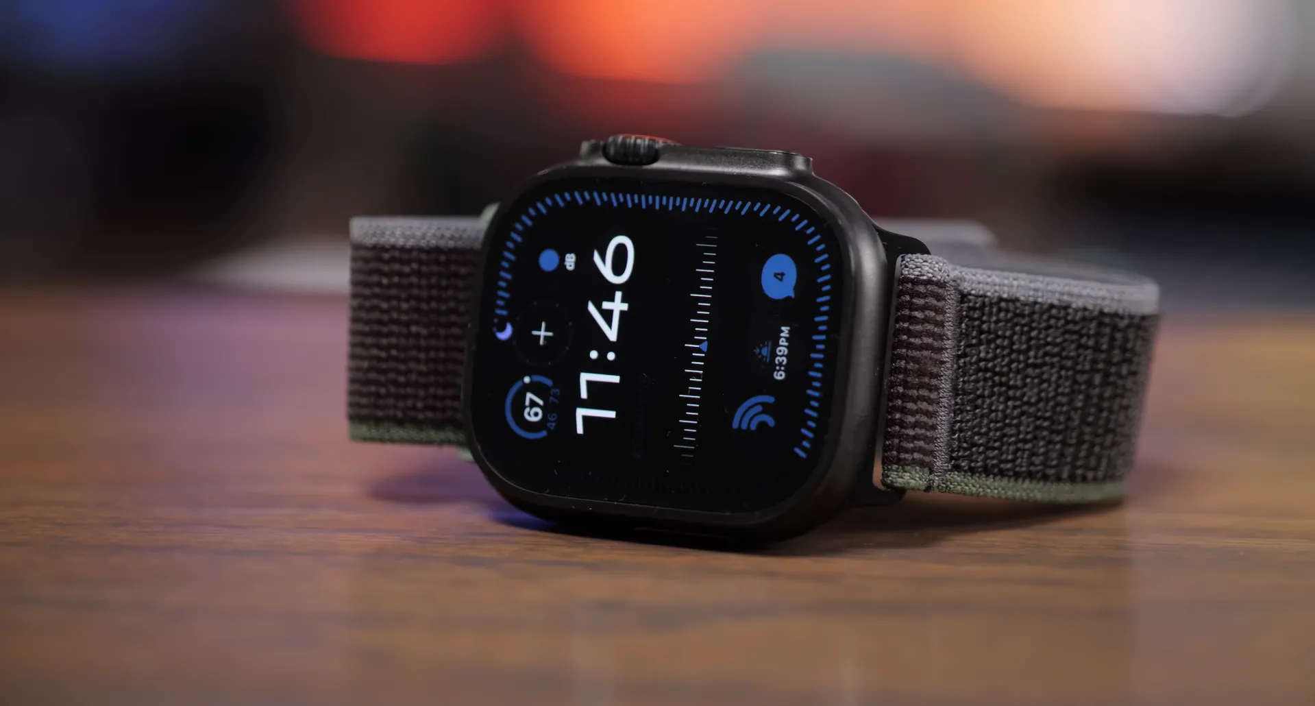 Apple Watch Ultra 3 Black Titanium de 49mm așezat pe un birou din lemn, cu ecranul luminos afișând un cadran digital