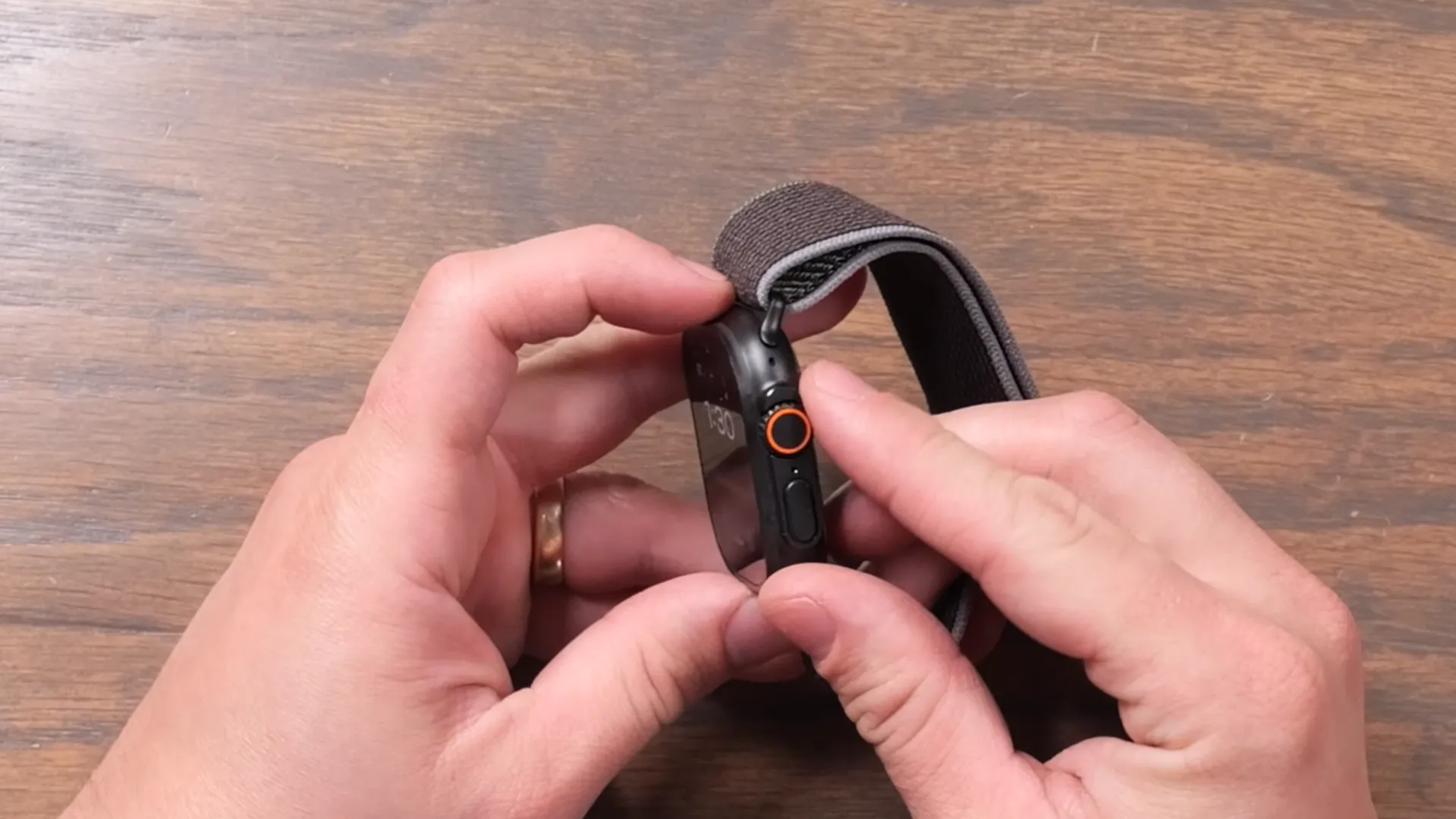 Utilizator operând butonul lateral și Digital Crown-ul cu inel portocaliu pe Apple Watch Ultra 3