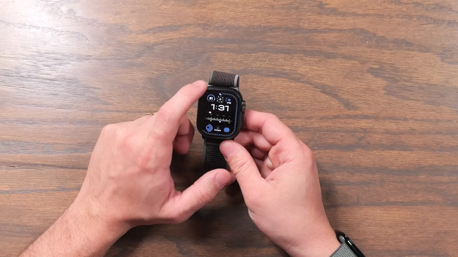 Hands-on cu Apple Watch Ultra 3 Black Titanium afișând un cadran modular cu complicații pentru vreme și activitate