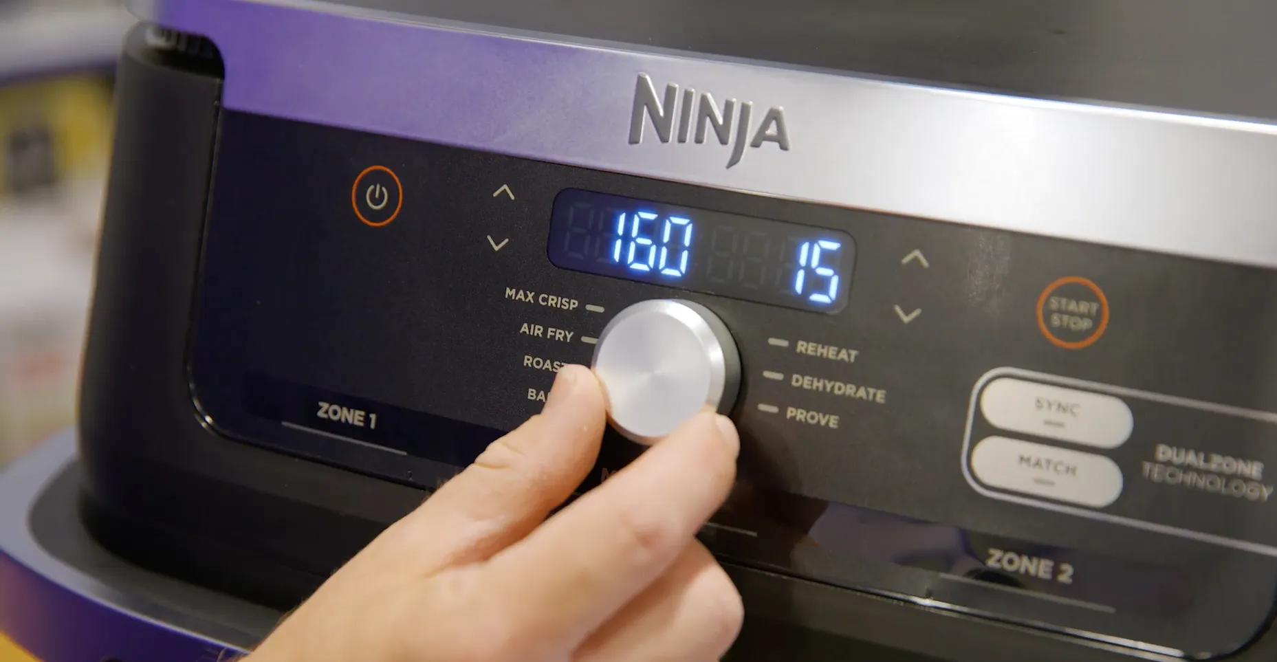 Utilizator rotind butonul central al friteuzei Ninja Foodi pentru a seta temperatura la 160 de grade și timpul la 15 minute