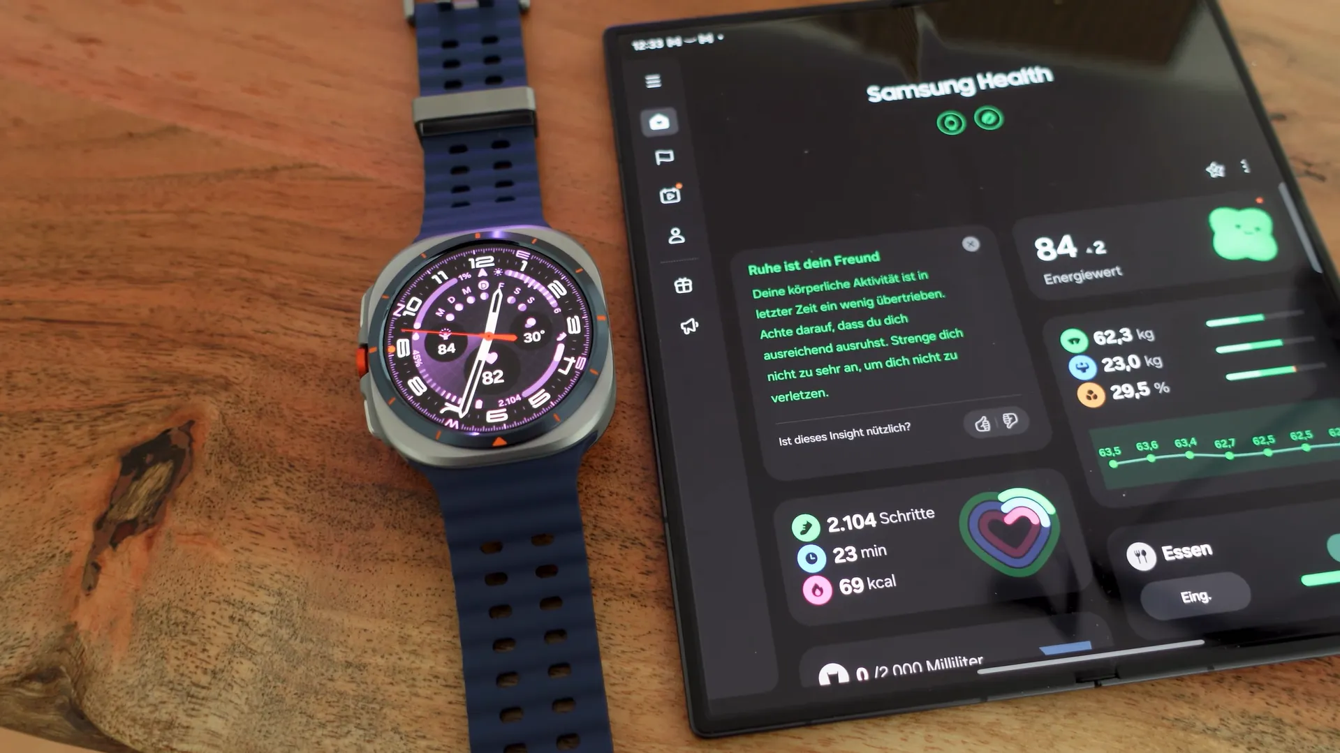 Samsung Galaxy Watch Ultra lângă un telefon pliabil afișând Energy Score de 84 în aplicația Samsung Health