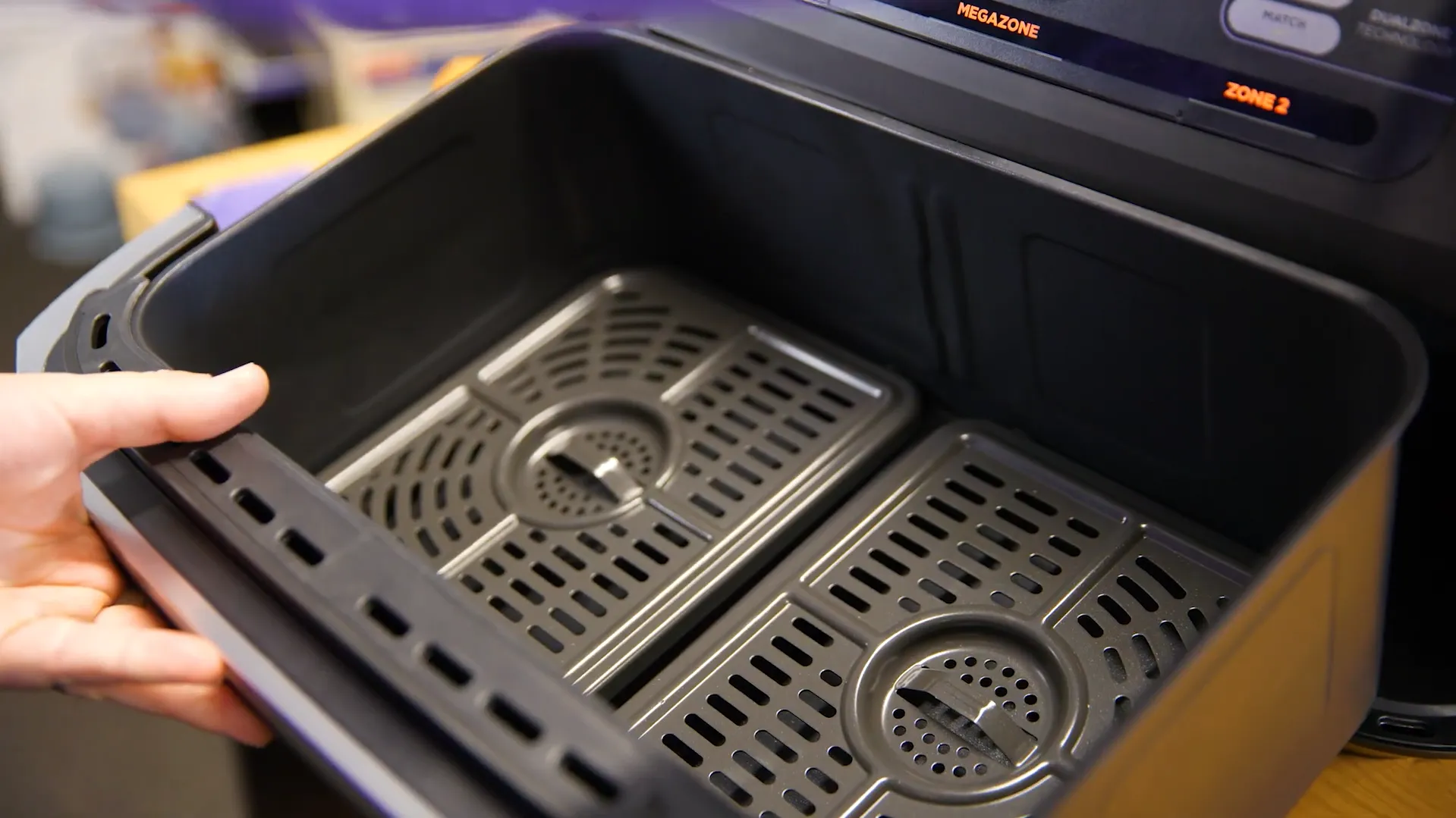 Sertarul principal al friteuzei Ninja deschis, fără separatorul median, arătând cele două grătare de pe fundul compartimentului uriaș